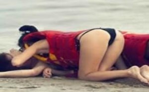 两个女人的在给男人做人工呼吸？其中一个在干嘛